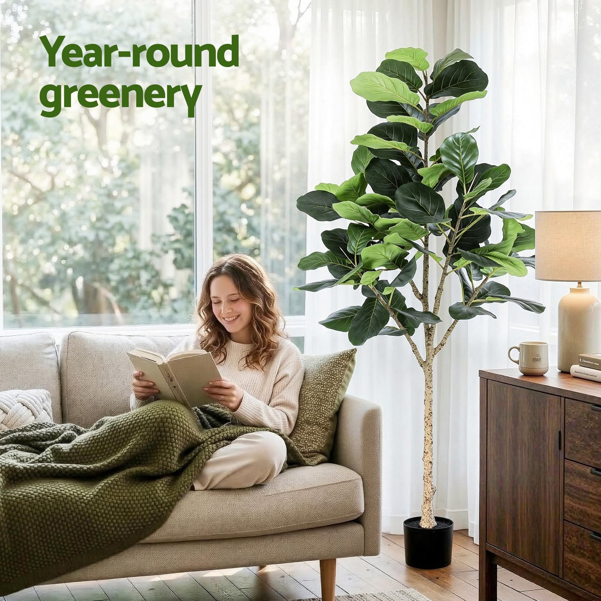 Artificial fiddle leaf fig tree with lifelike green leaves in a black pot next to a sofa