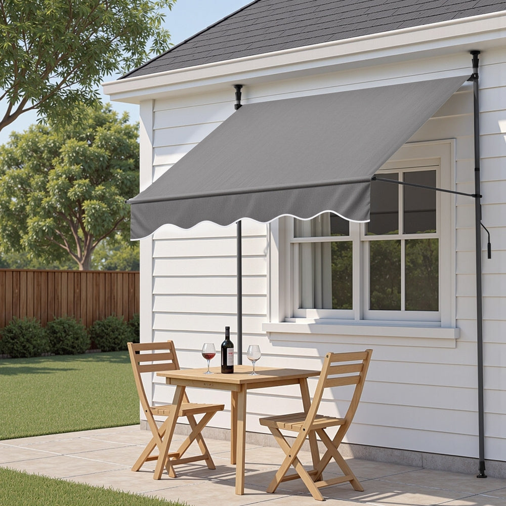 Grey door canopy awning with scalloped valance and pivot arm supports on exterior wall