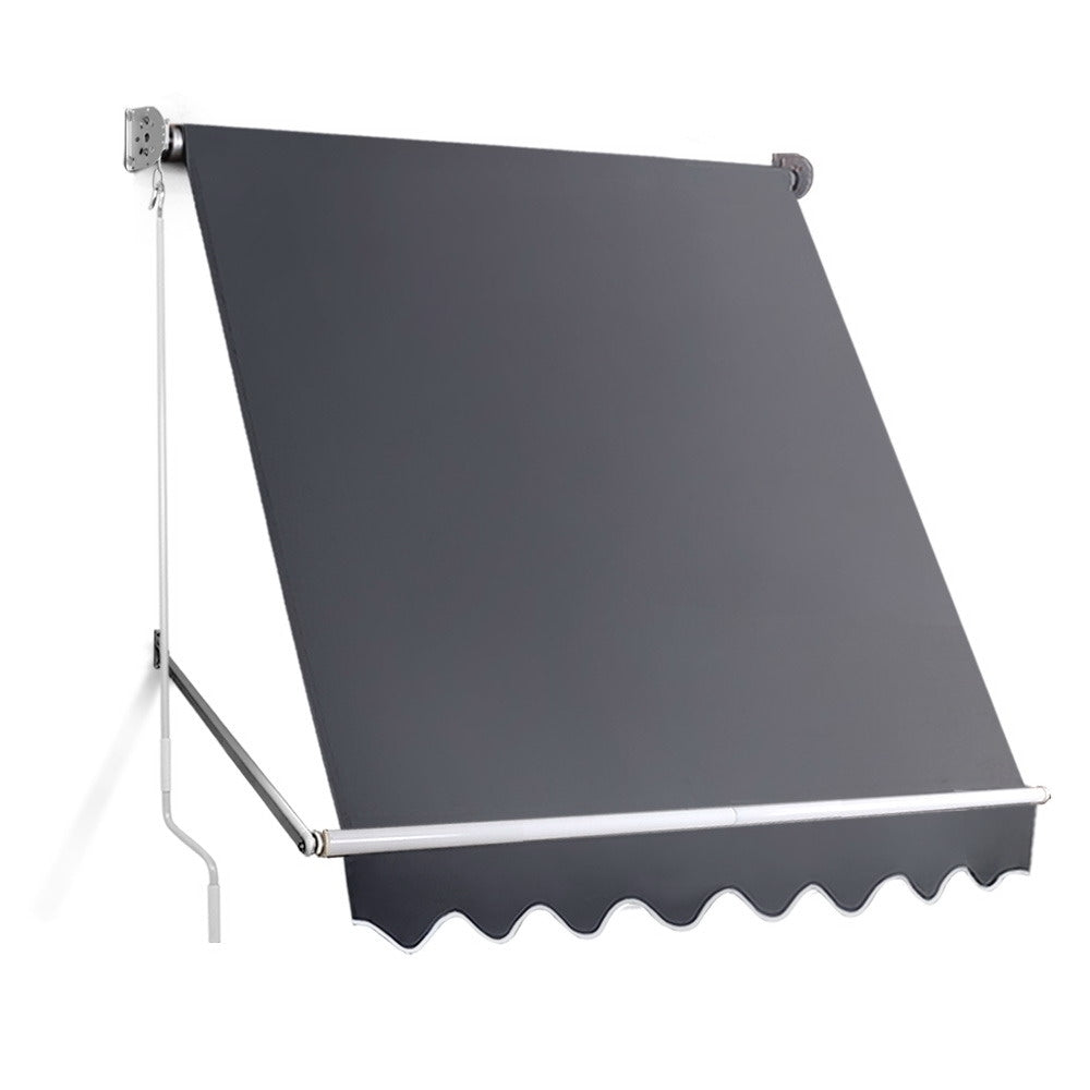 Outdoor window awning with dark gray fabric, white pivot arms, and scalloped front valance