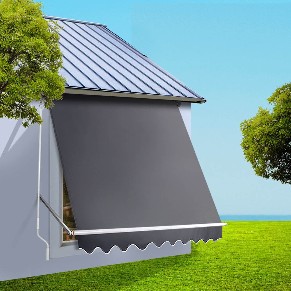 Outdoor window awning with dark gray canopy fabric, white support arms, and scalloped valance