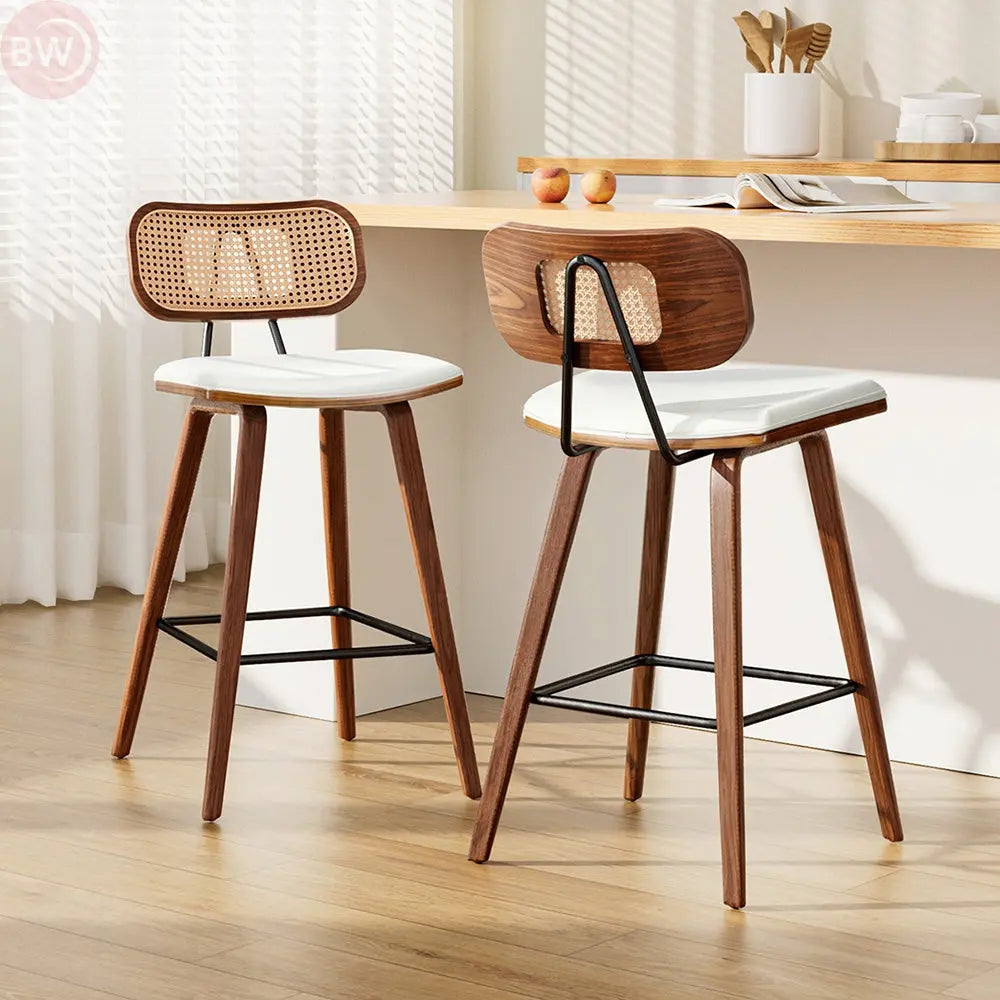 Two rattan bar stools with woven backs, white seats, wood legs, and black footrests
