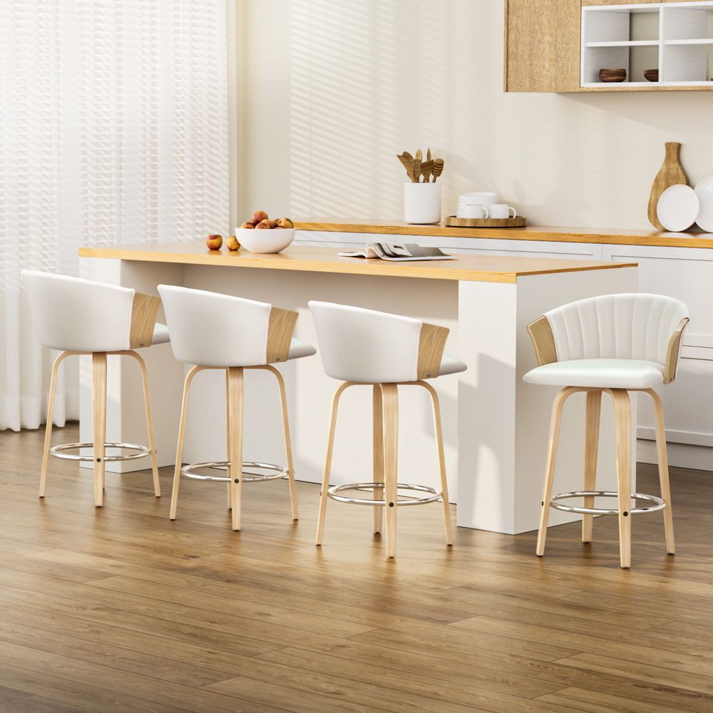 Set of four white padded swivel bar stools with light wooden frames and chrome footrest.