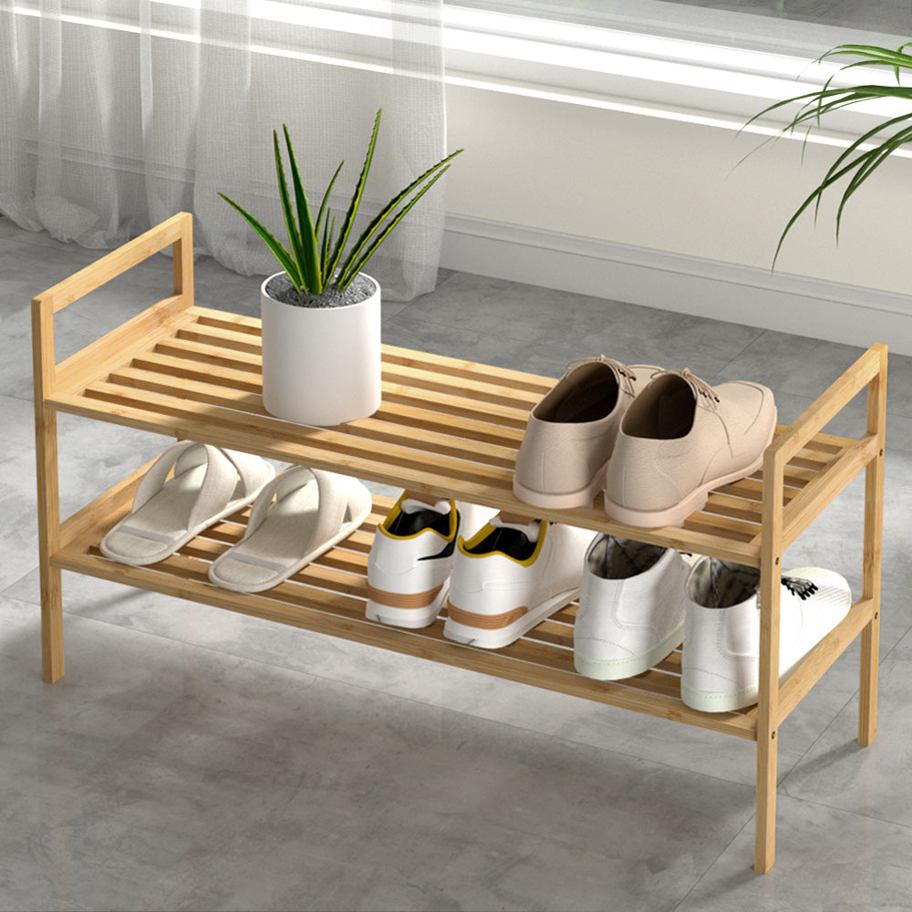 Two-tier bamboo shoe rack with open shelves and side rails, holding several pairs of shoes.