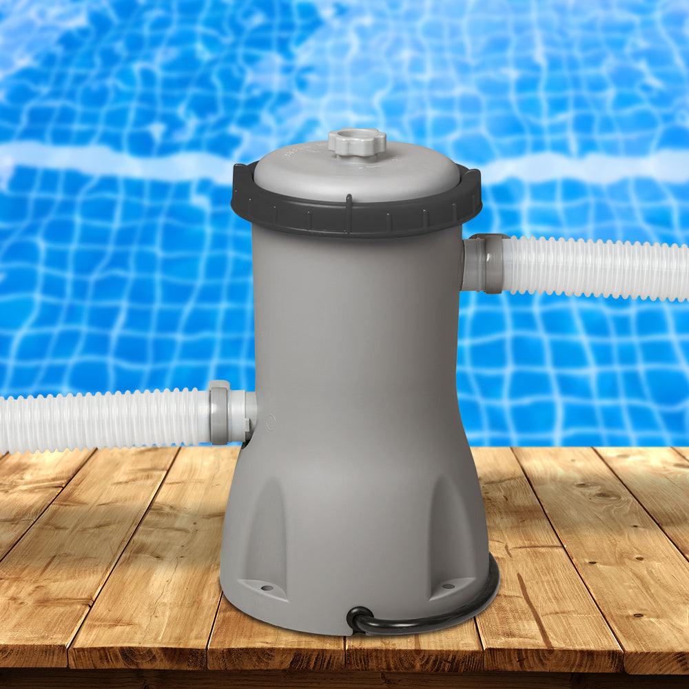 Pool filter cartridge pump with blue-filter top and hose connections beside pool