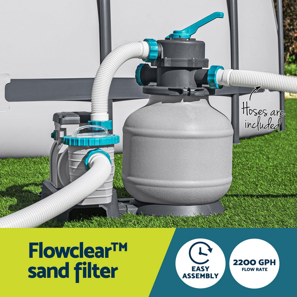 Sand filter pump with grey tank and teal valve connected to white garden-style hoses