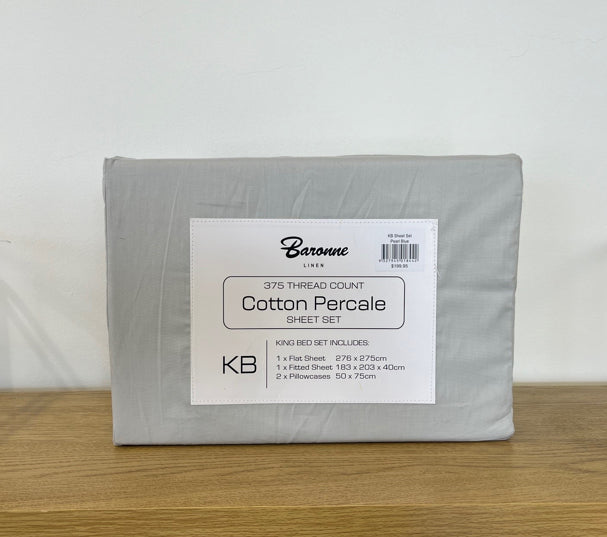 Packaged cotton percale sheet set with Baronne branding on a wooden surface.