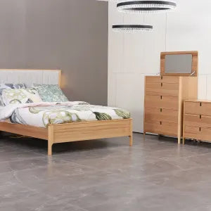Wooden bed and dresser in a room with gray walls and flooring.