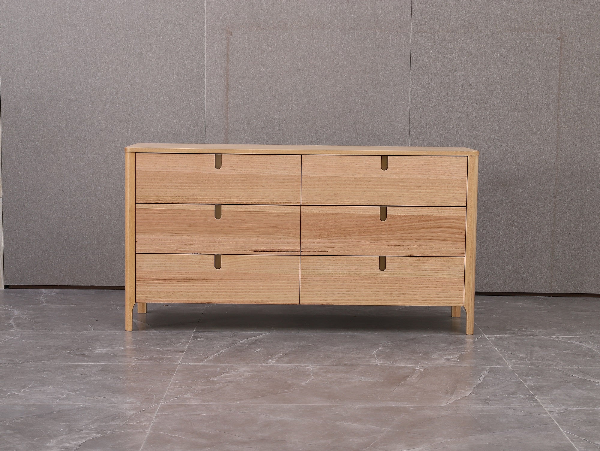 Wooden dresser with four drawers on a gray floor and background
