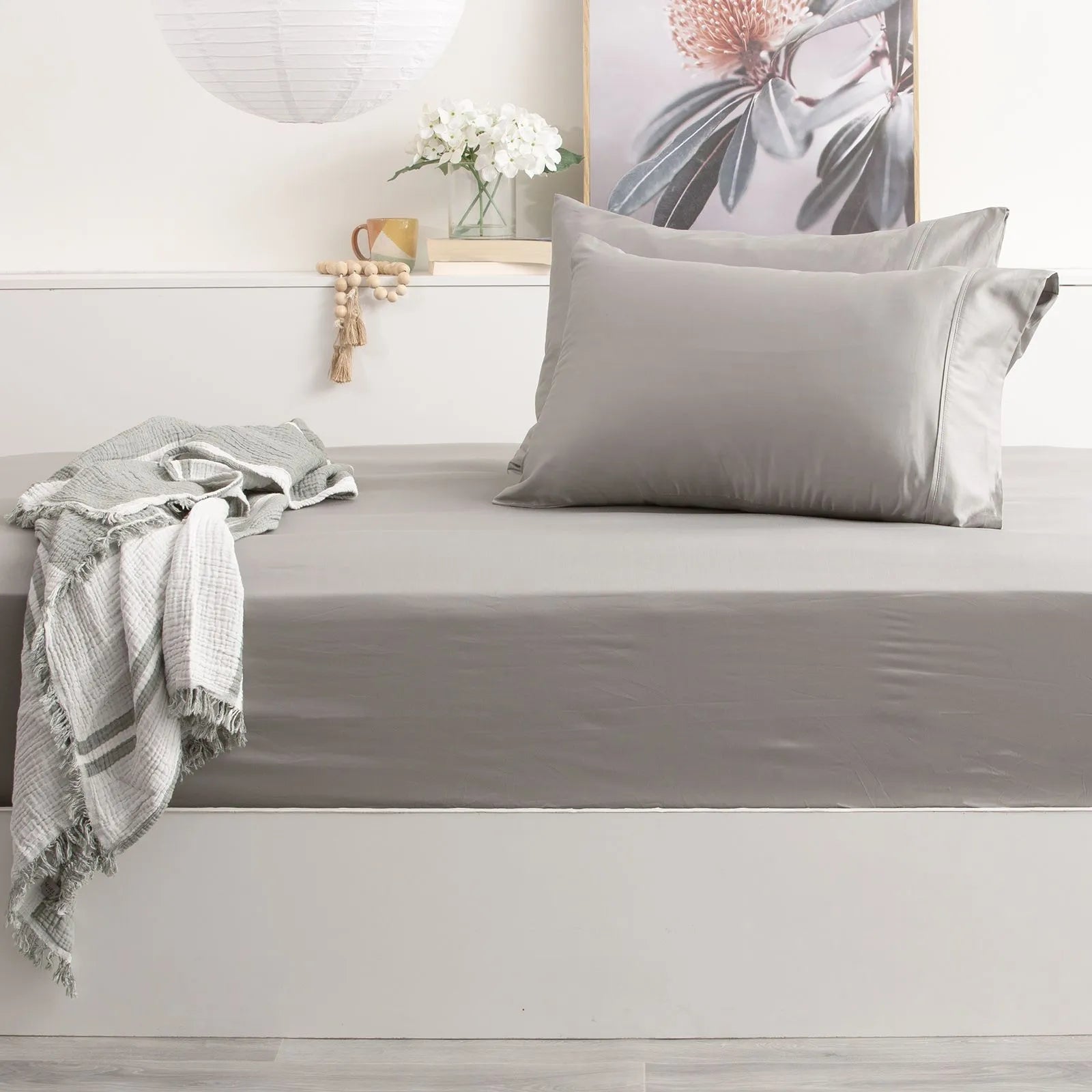 Gray bedding set on a bed with a decorative pillow and blanket.
