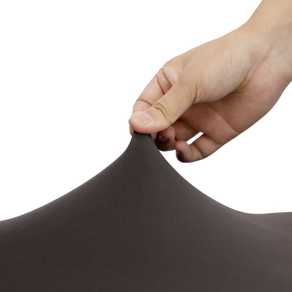 Hand adjusting a dark grey spandex chair slipcover with snug elastic edge