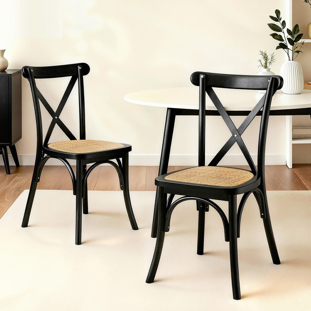 Two dining chairs with black X-back frames and woven rattan-style beige seats.