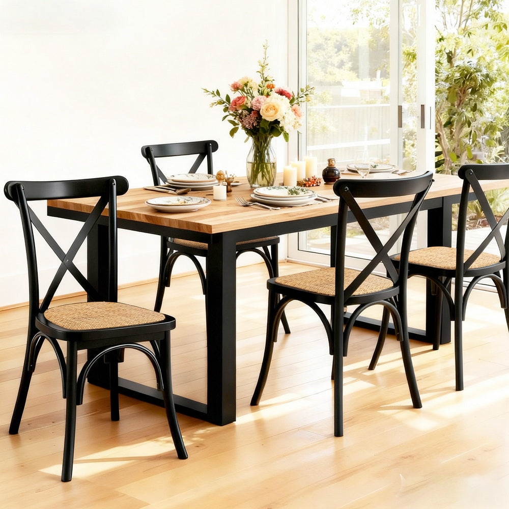 Dining chairs with black frames and woven seats around a table