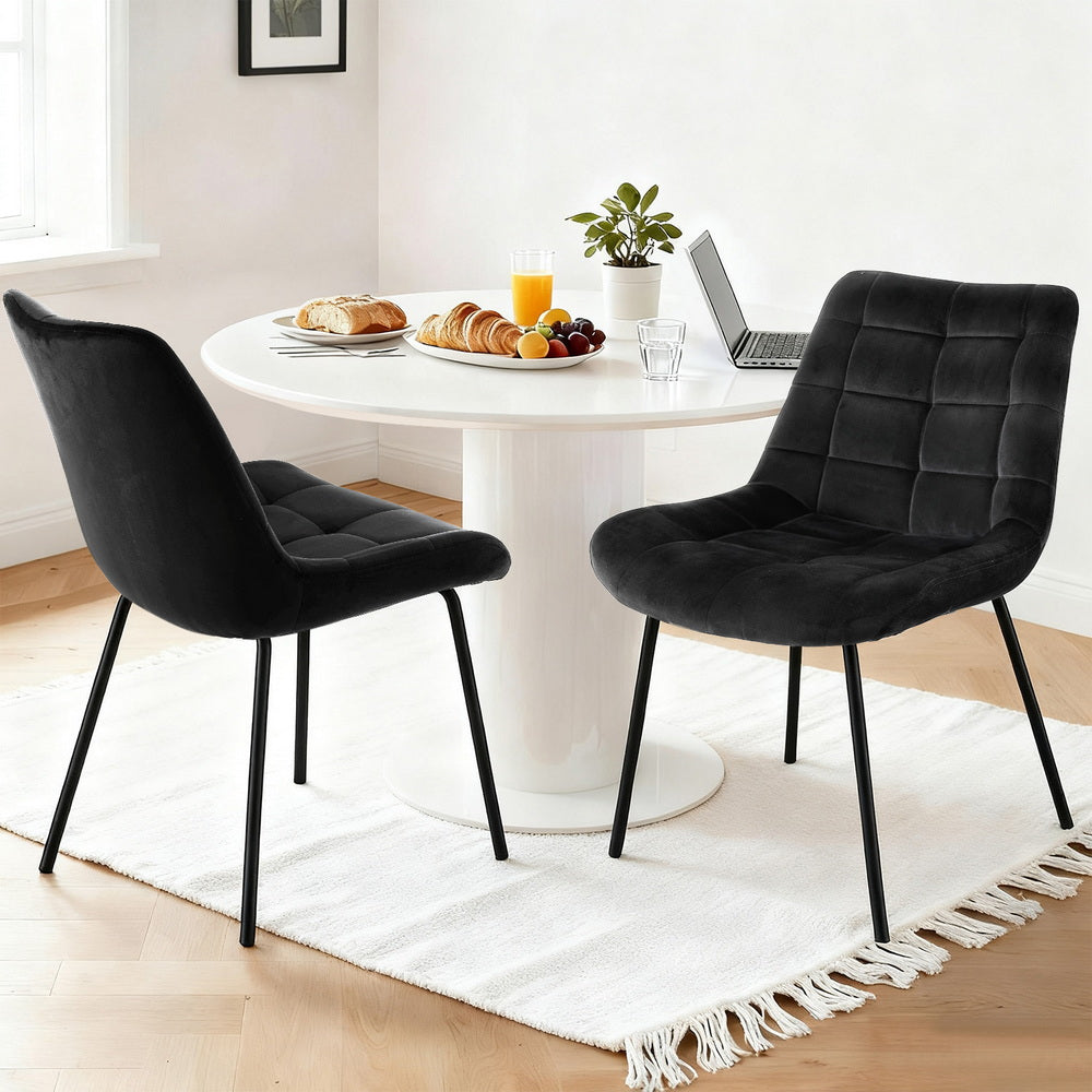Black velvet armless dining chair pair with curved back, cushioned seats, and black metal legs