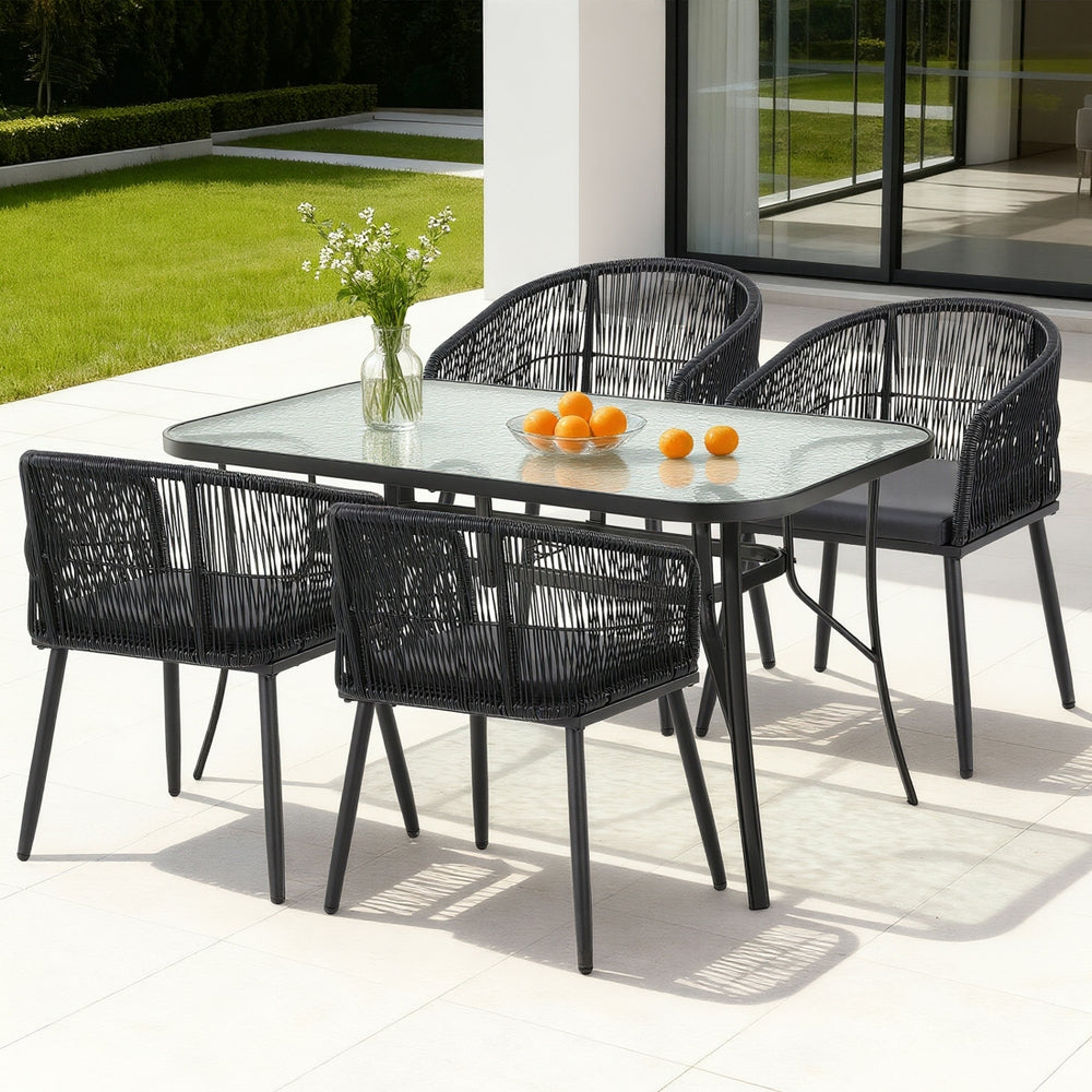 Black outdoor dining table with tempered-glass top and four woven chairs