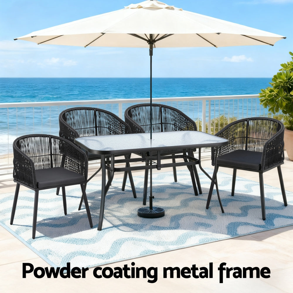 Outdoor dining set with umbrella, glass-topped table, and four black woven chairs