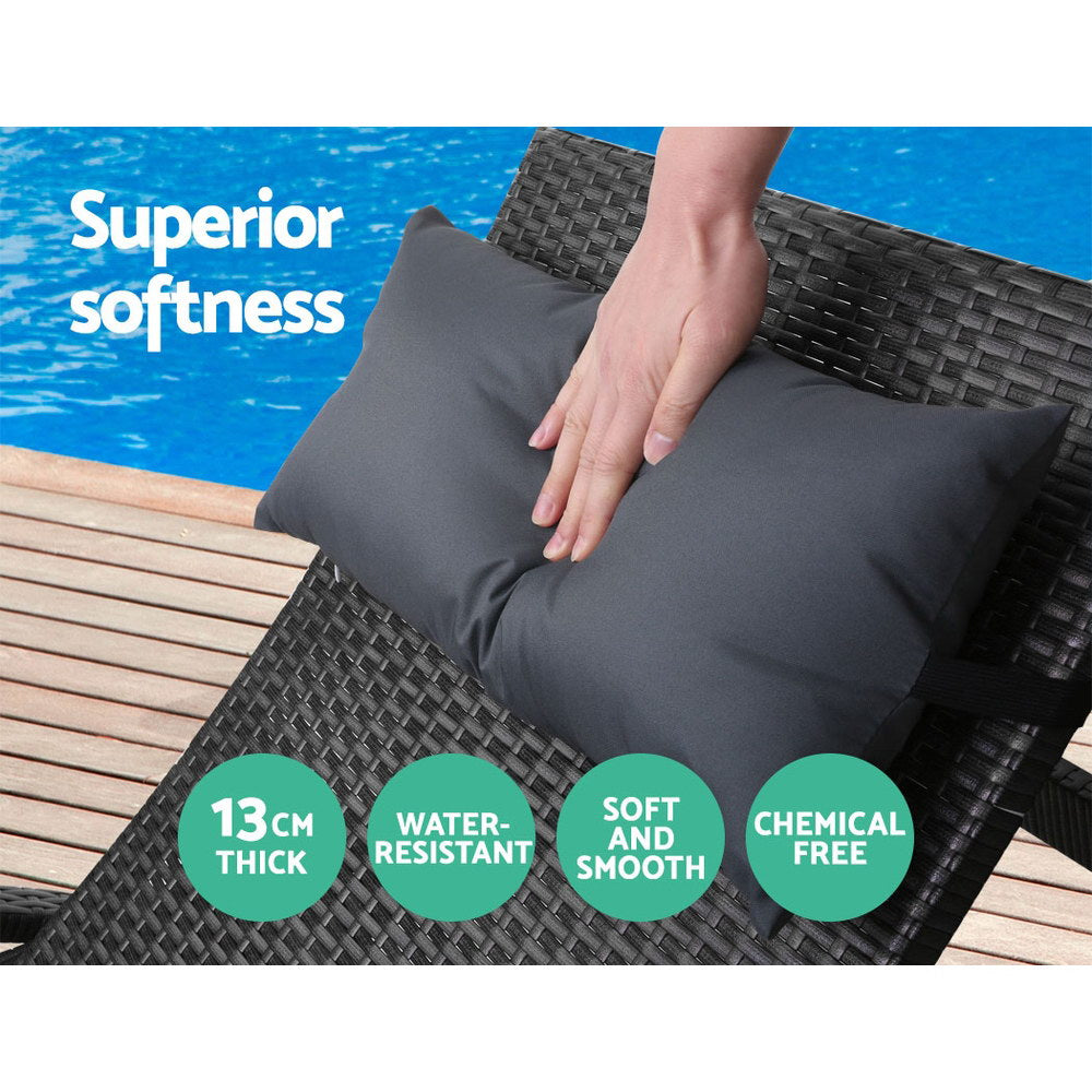 Outdoor wicker lounge chair with thick black seat cushion and head pillow, on black frame