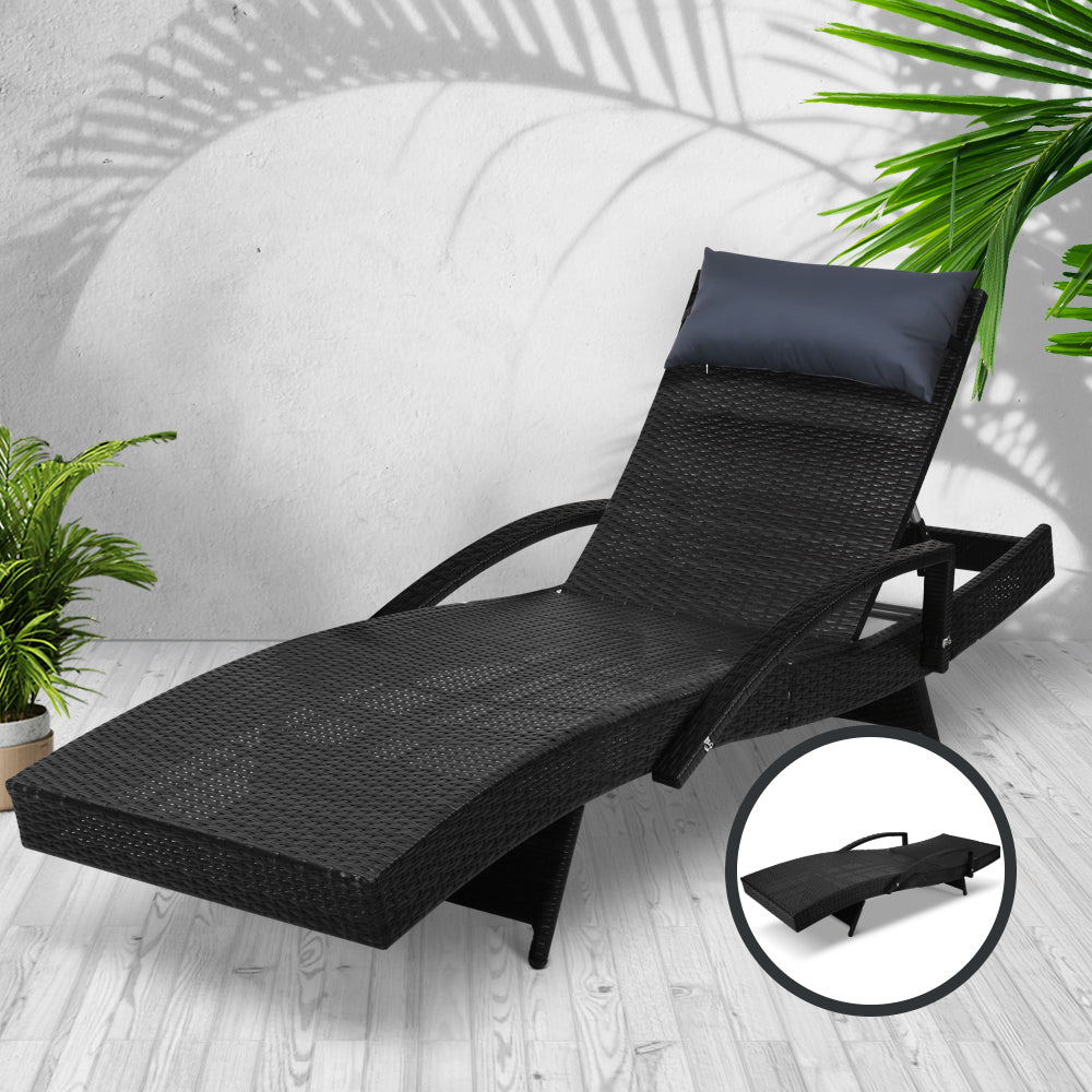 Adjustable outdoor wicker lounge chair with black cushion, head pillow, and curved armrests