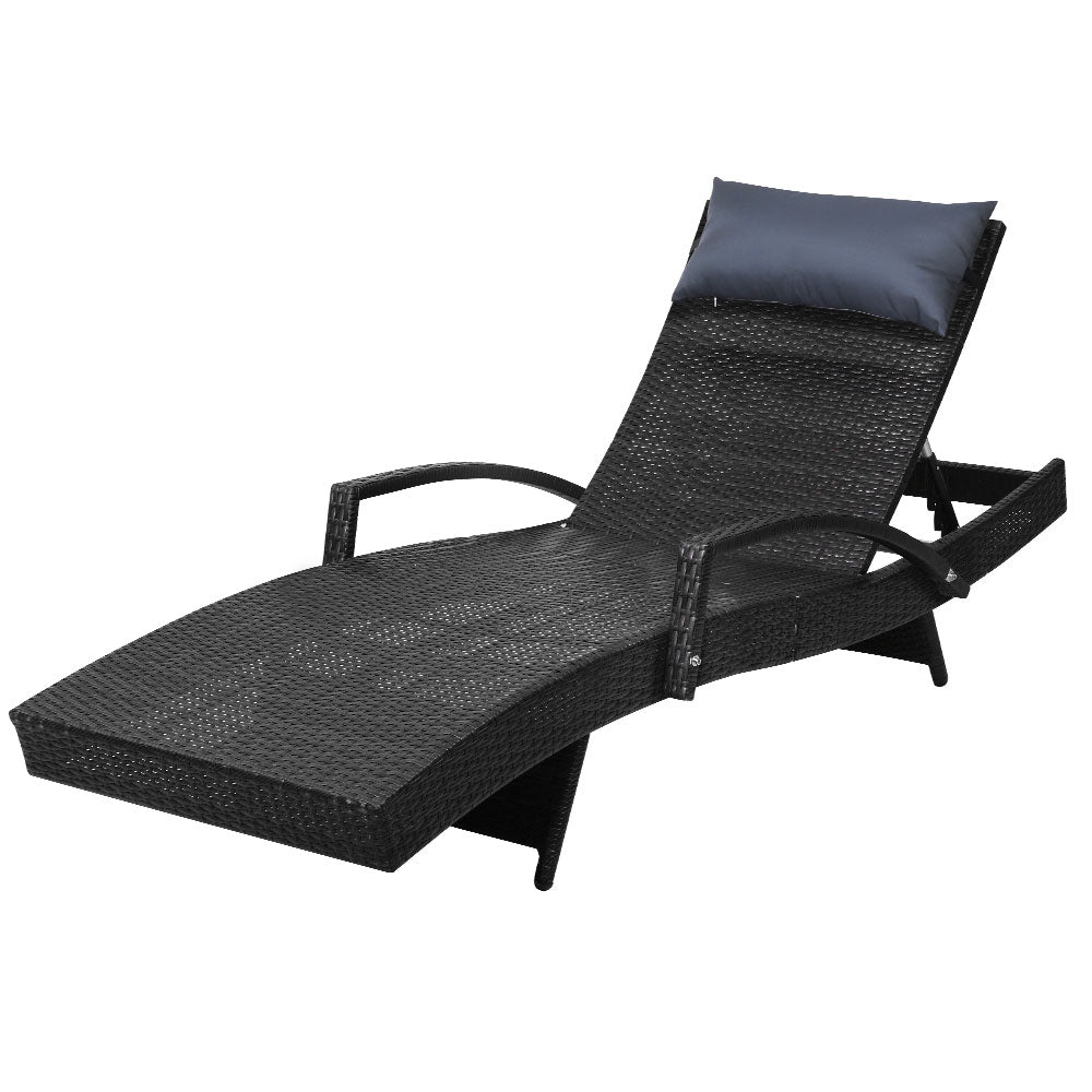 Outdoor wicker lounge chair with black seat cushion, head pillow, and armrest support