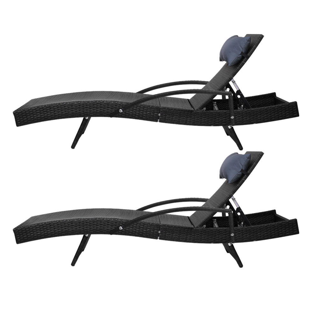 Two black woven wicker reclining sun loungers with padded headrests and curved base supports