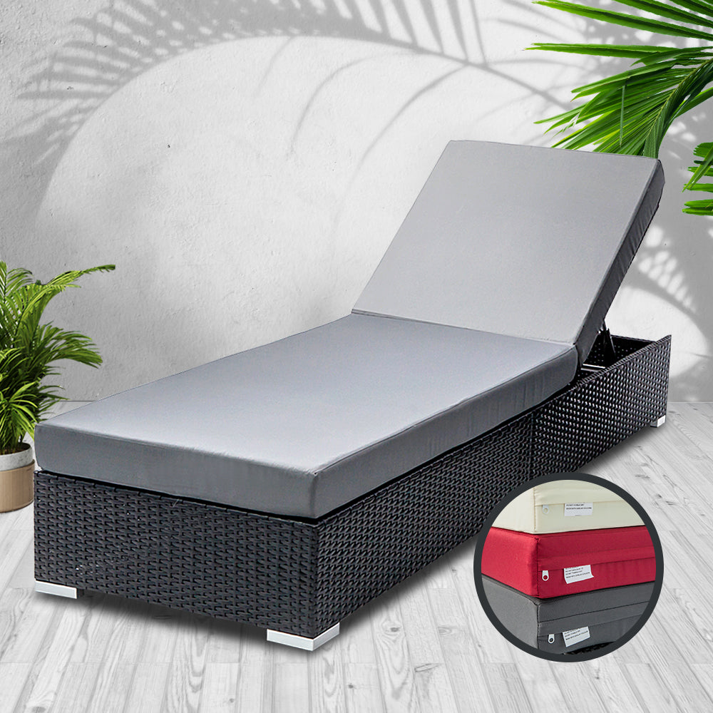 Black wicker sun lounger with light gray cushions and lift-up storage section
