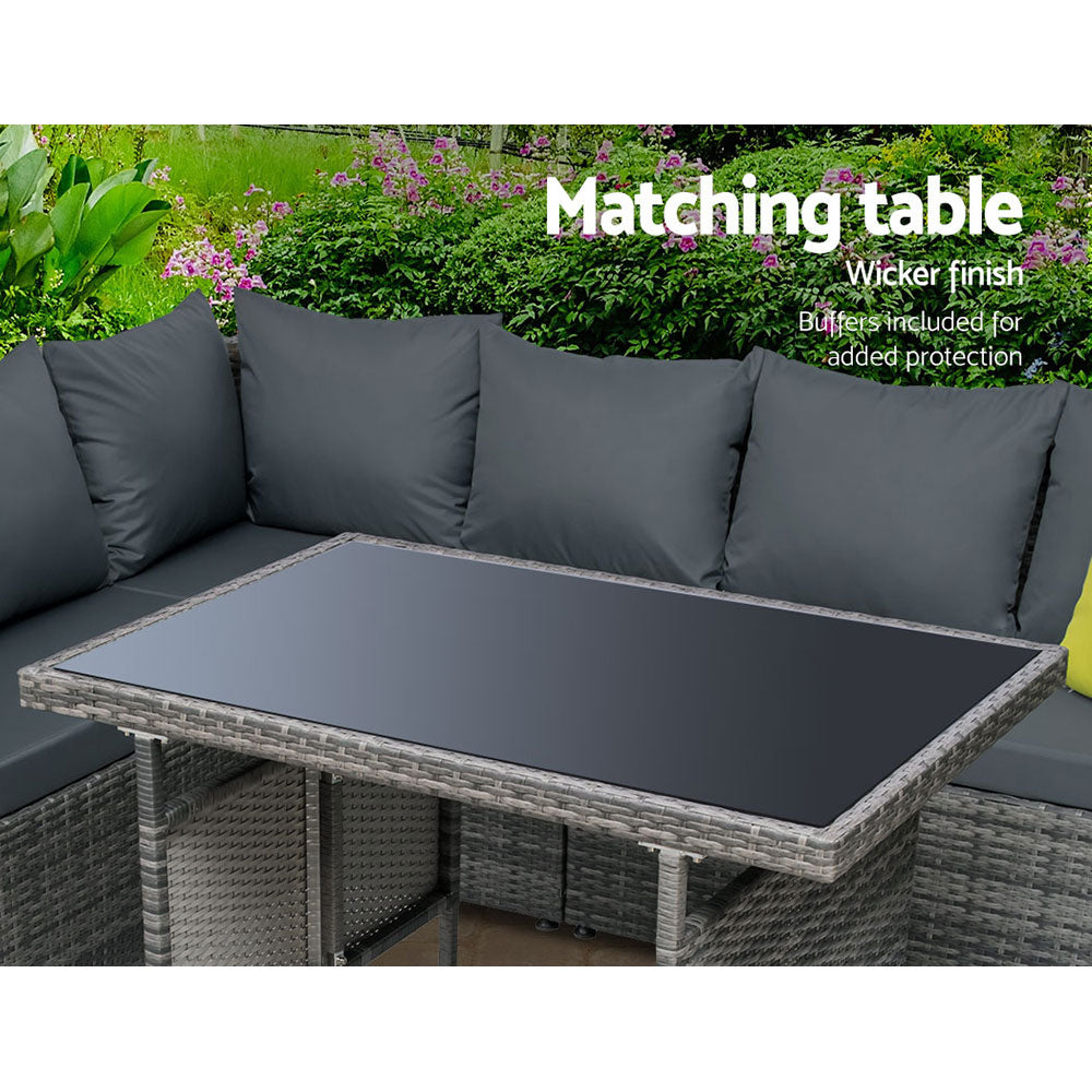 Outdoor dining set with grey wicker-look table and dark back cushions, yellow accent pillows