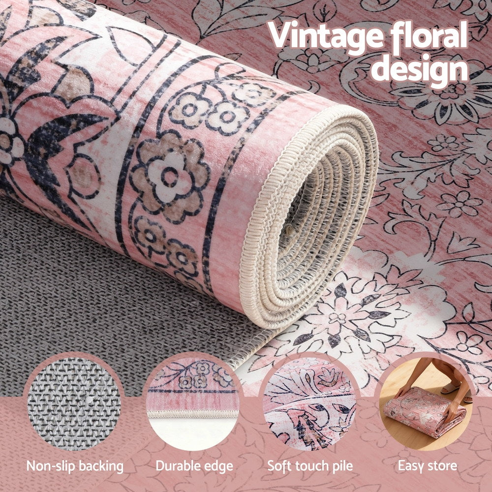 Rolled pink vintage floral rug showing textured pile and stitched edge trim.