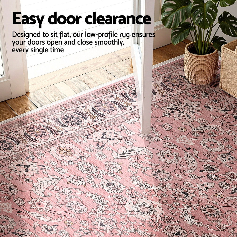 Pink vintage floral area rug under a doorway, low-profile flat pile.