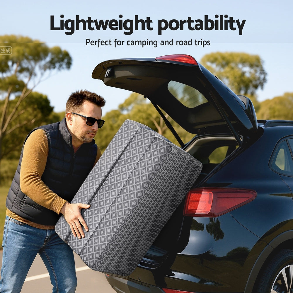 Trifold memory foam mattress in gray geometric cover being lifted for travel