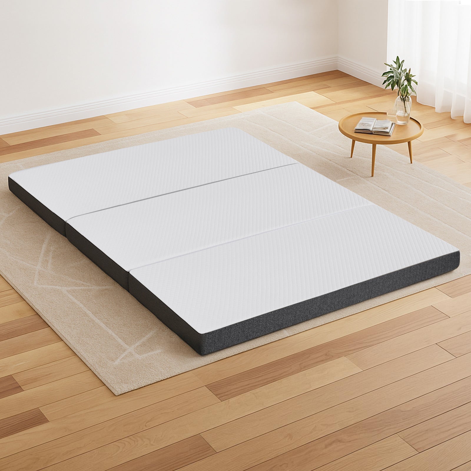 Tri-fold mattress with white quilted top and dark gray edges on a beige base
