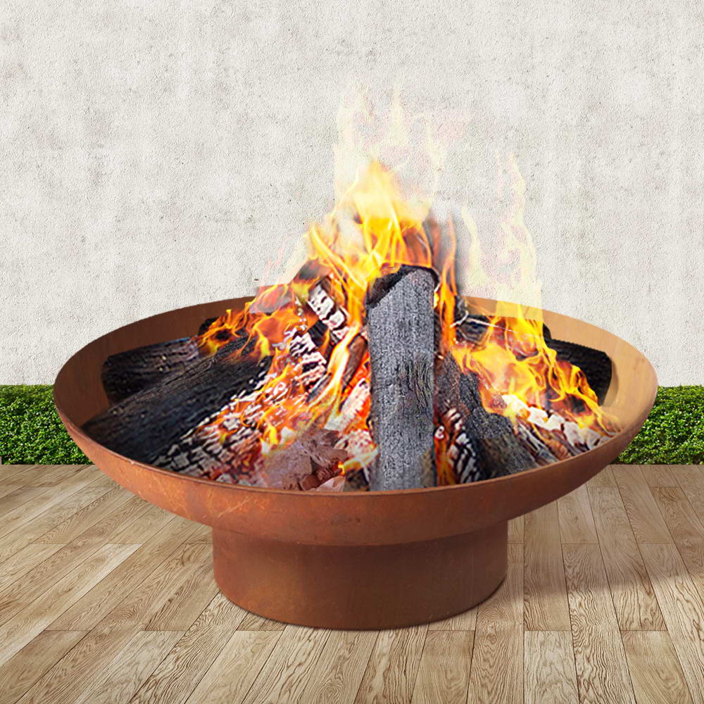 Rust-brown cast iron fire pit bowl with bright flames and burning logs in the basin