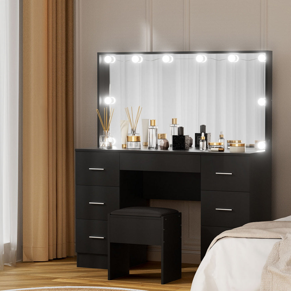 Black dressing table vanity with illuminated mirror, drawers, and cushioned stool