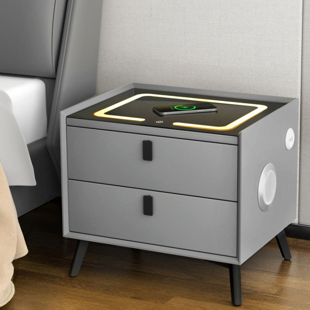 Grey bedside table with lit wireless charging pad showing a device and 2 drawers