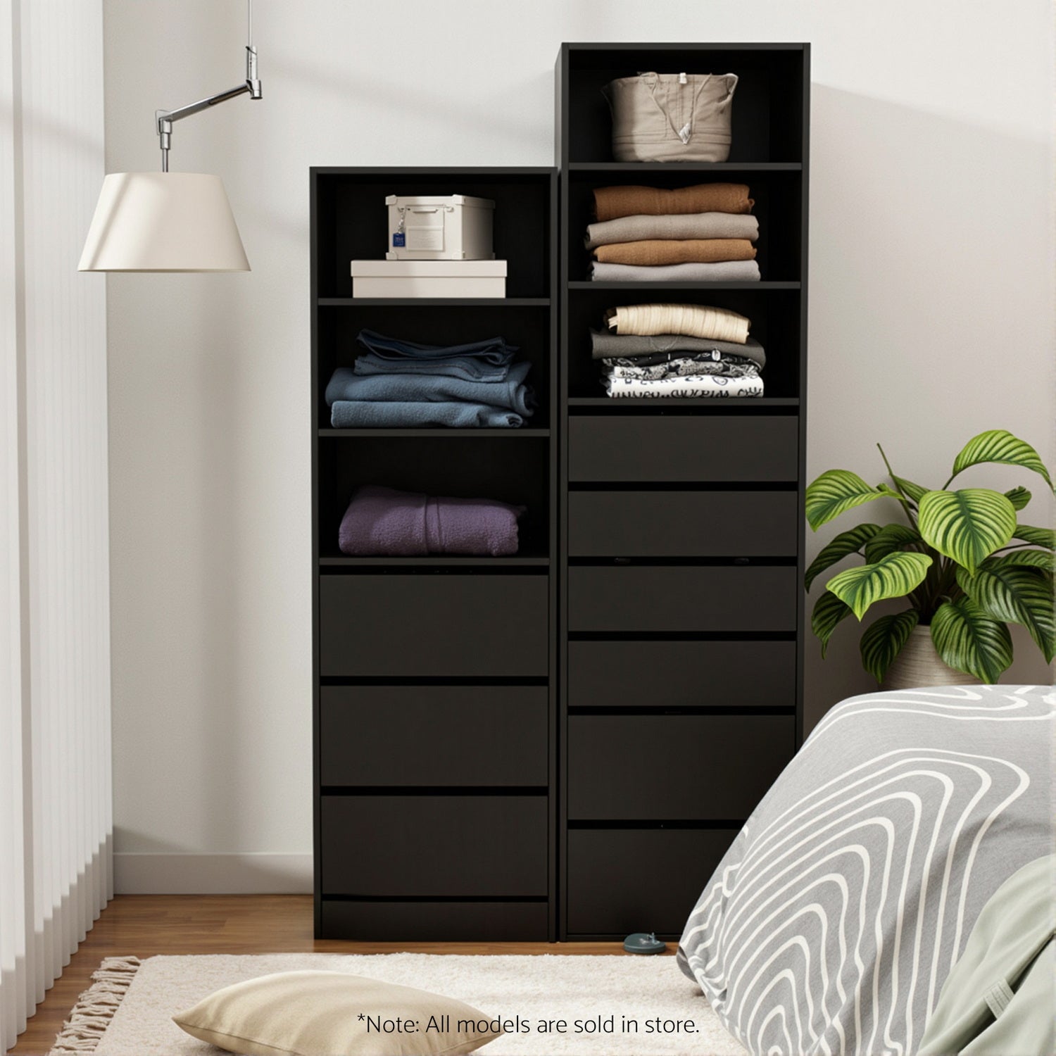 Black tallboy cabinet open with folded linens in shelves and drawer fronts