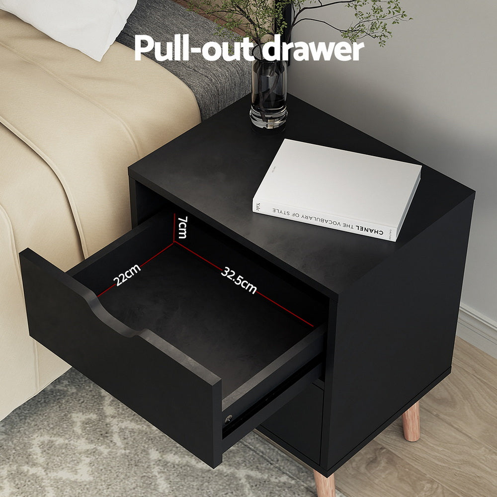 Black bedside table with one open drawer and wooden legs