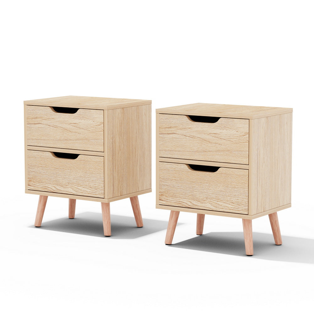 Light pine bedside table set with two drawers, black handle cutouts, and wooden tapered legs.