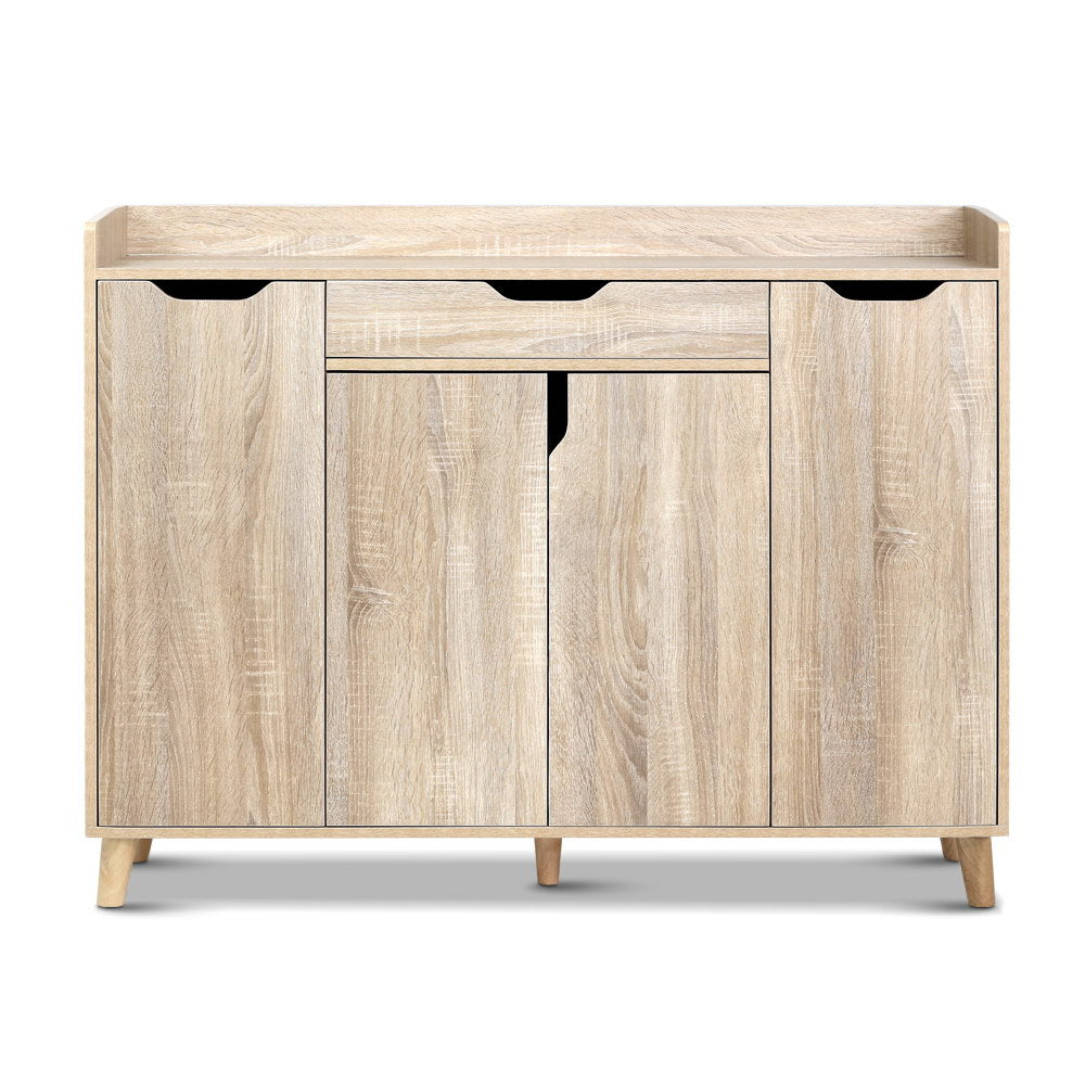 Shoe rack cabinet with two doors and center drawer, black handle cutouts, light oak