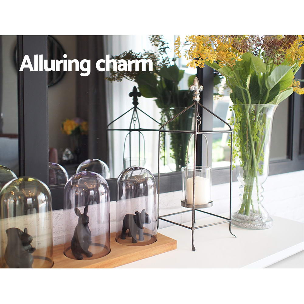 Light-colored console table top with candle lanterns, glass domes, and decor items
