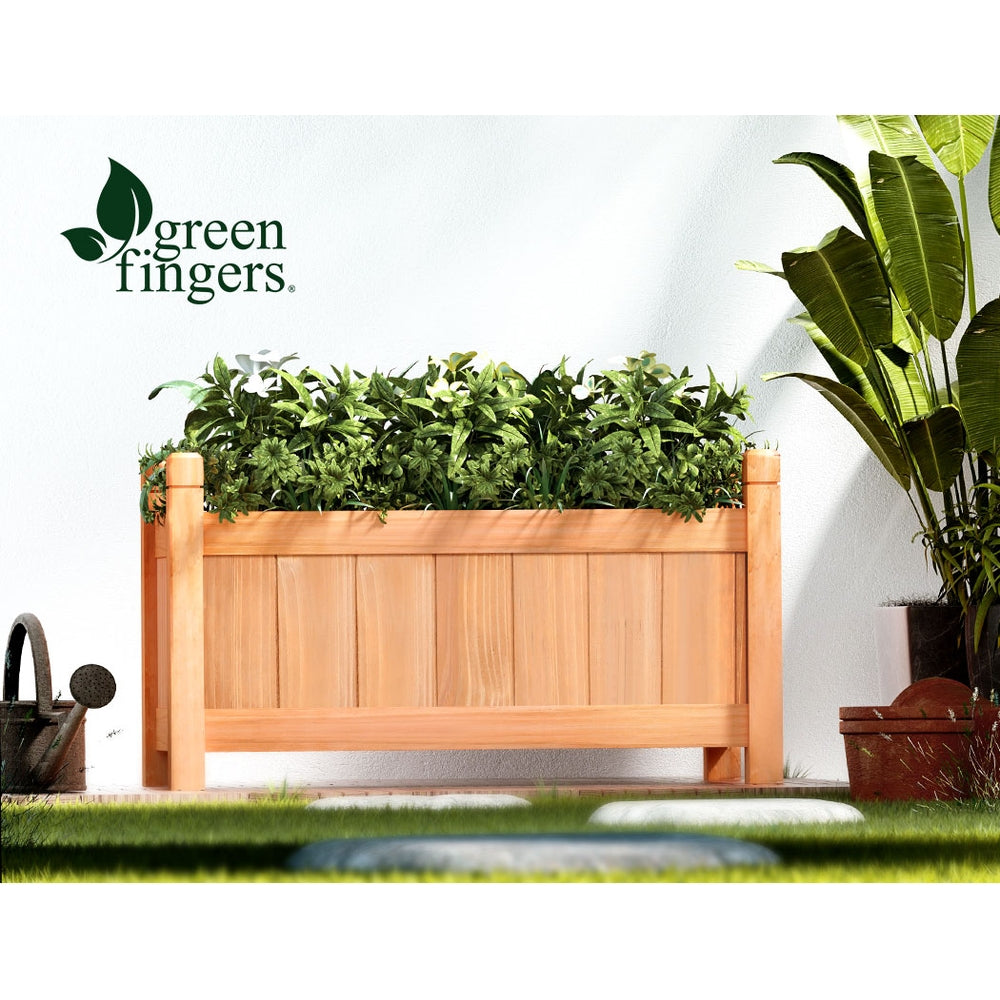 Light wooden raised planter box with leafy plants and four corner posts.