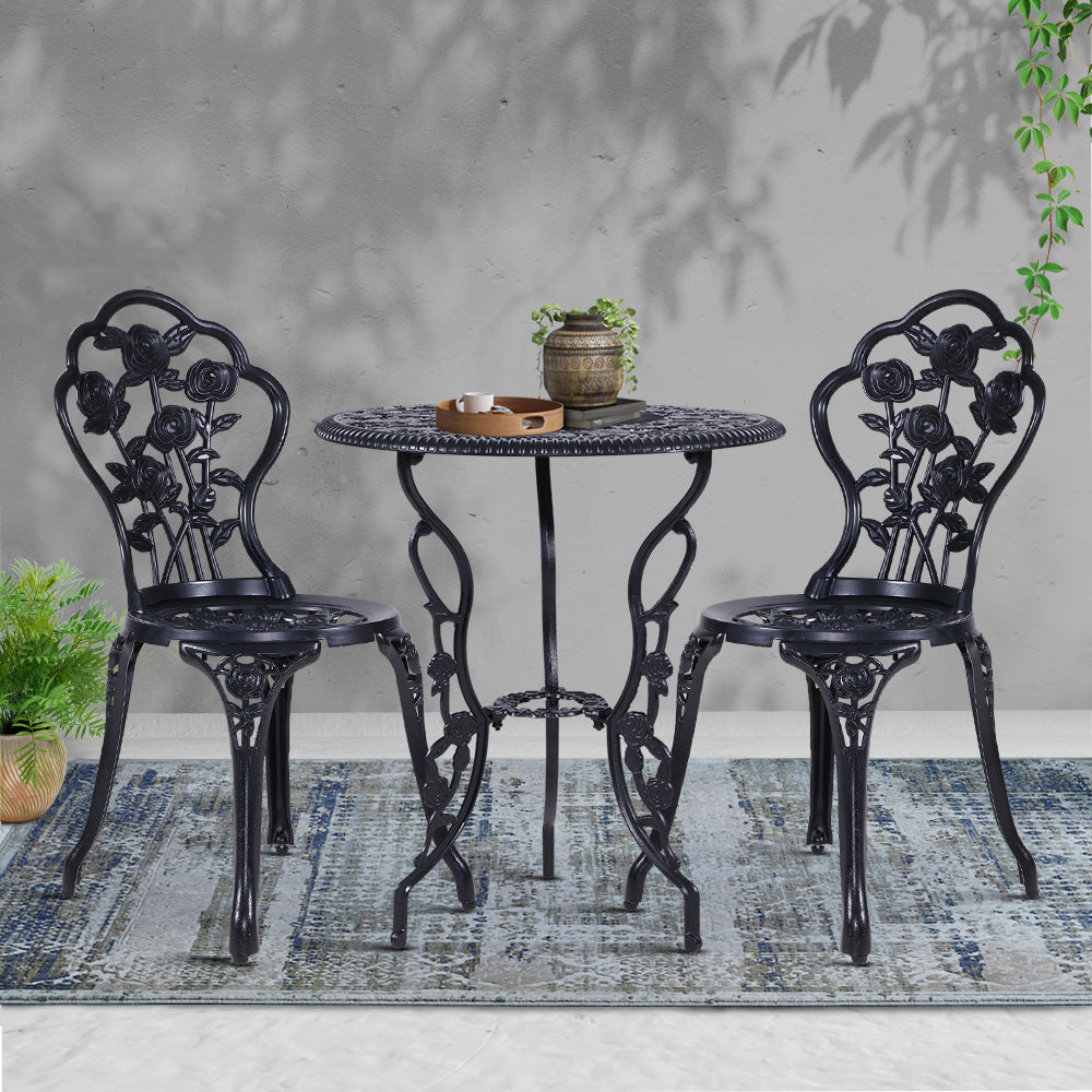 Black bistro set with rose-pattern chairs and round table holding a small planter