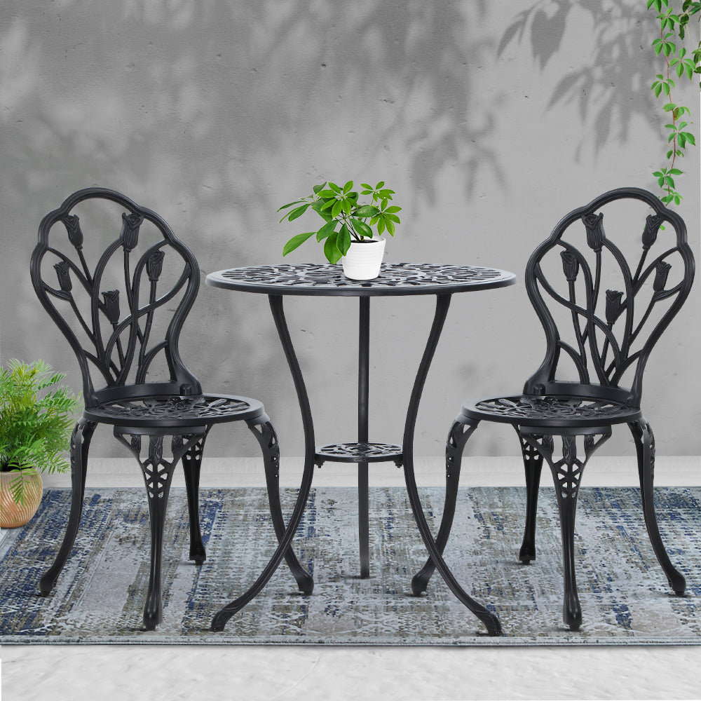 Black round bistro table with two tulip-backed chairs and potted plant on top