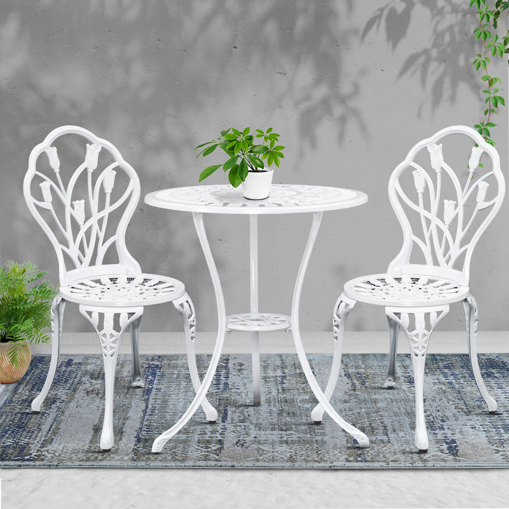 White bistro set: round table with potted plant and two ornate armchairs