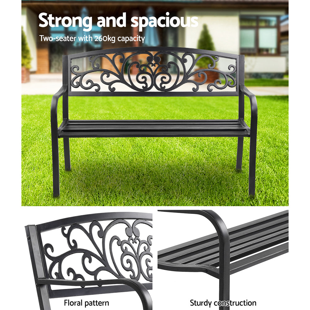 Black outdoor garden bench with ornate scroll back and slatted seat