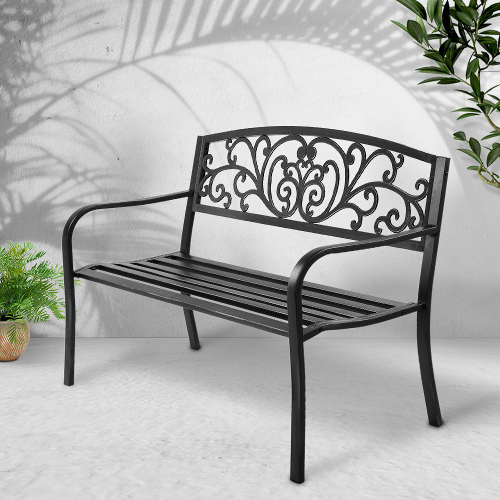Black metal outdoor bench with scrollwork backrest and slatted seat