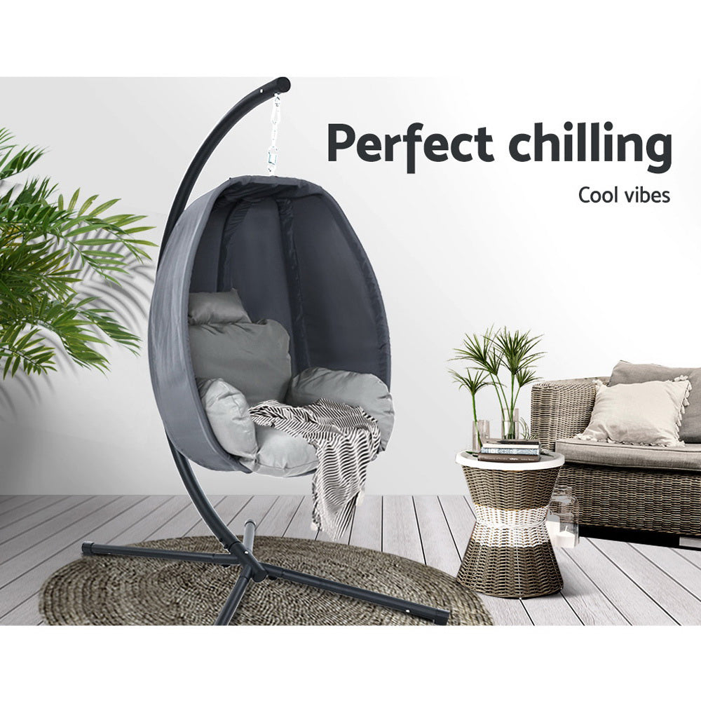 Egg swing chair with dark gray curved frame, black canopy, and light gray cushioned seat