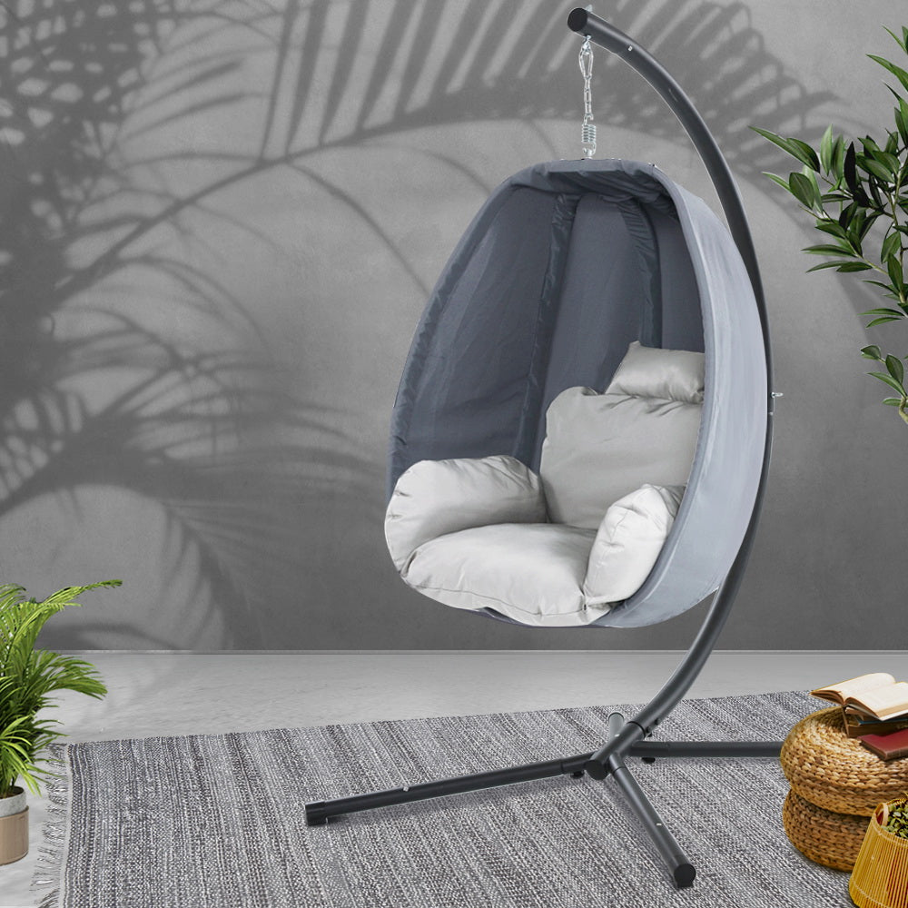 Egg swing chair with dark gray stand and black canopy over light gray seat cushions