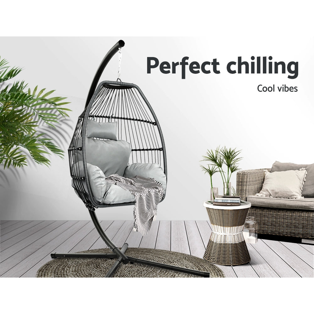 Hanging egg swing chair with grey cushions on black curved stand