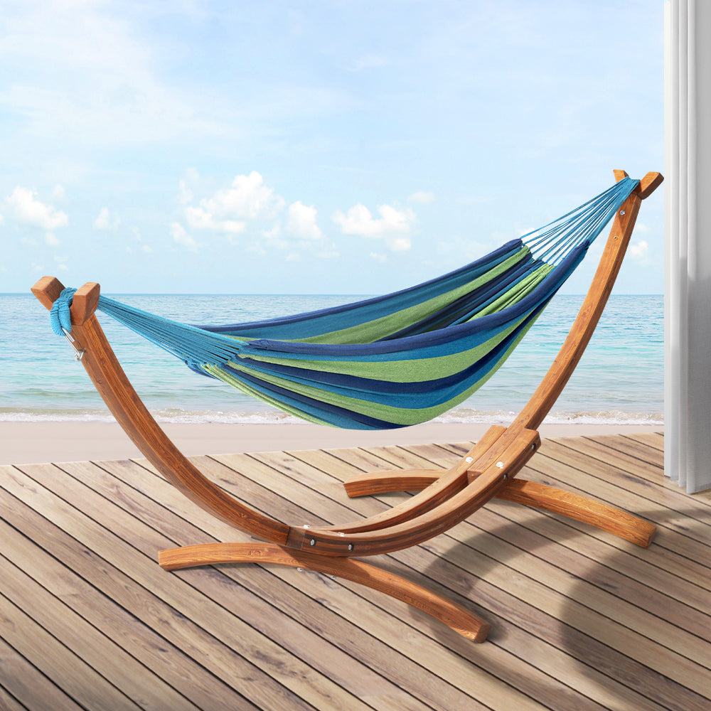 Outdoor hammock on a curved wooden stand with blue and green striped fabric