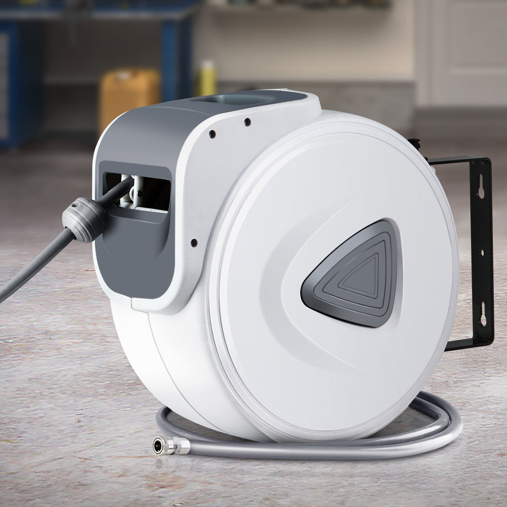Retractable air hose reel on floor with coiled hose, swivel outlet, and wall bracket