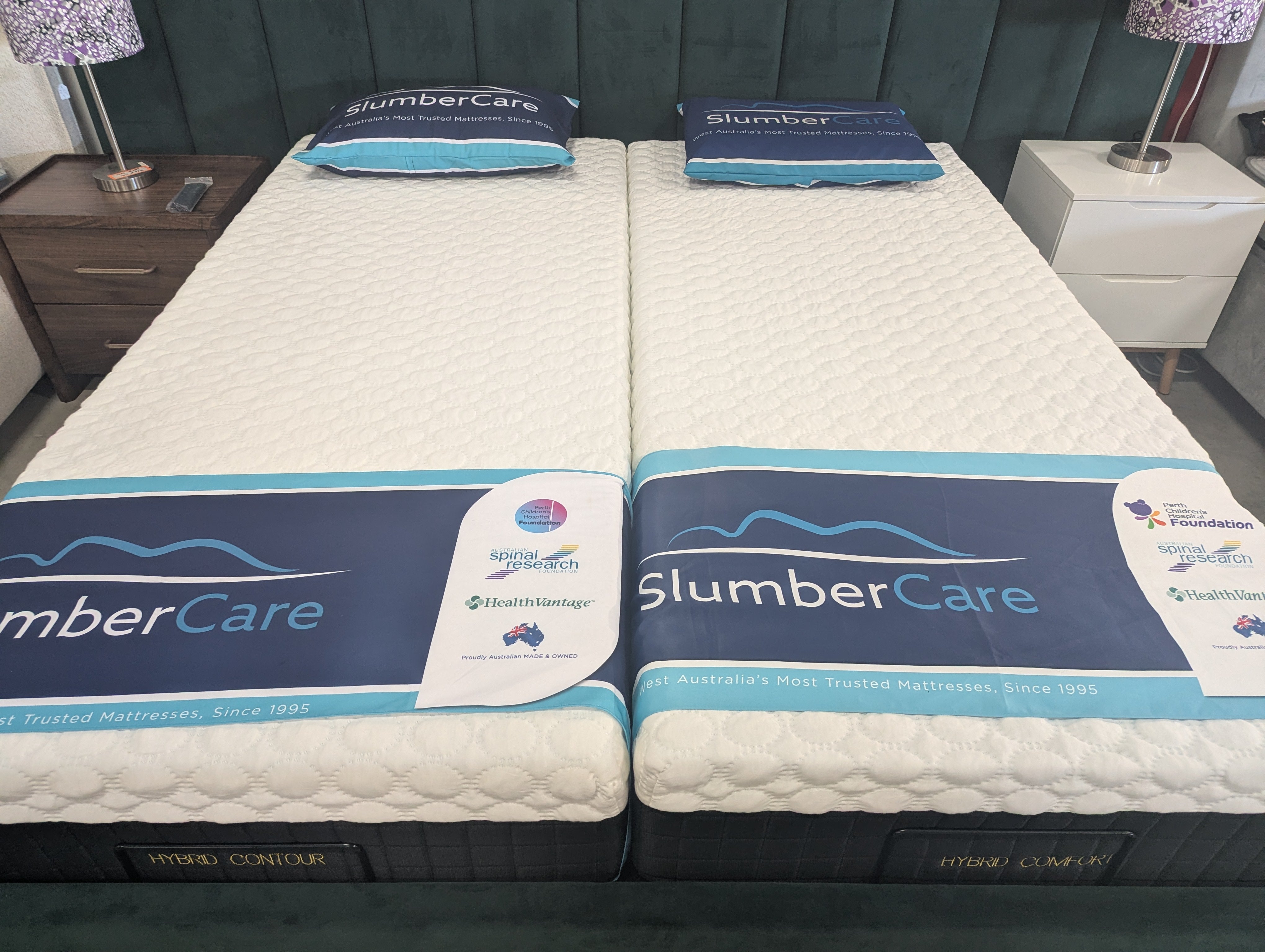 SlumberCare hybrid contour mattress pair, white quilted tops with blue bands and tags.