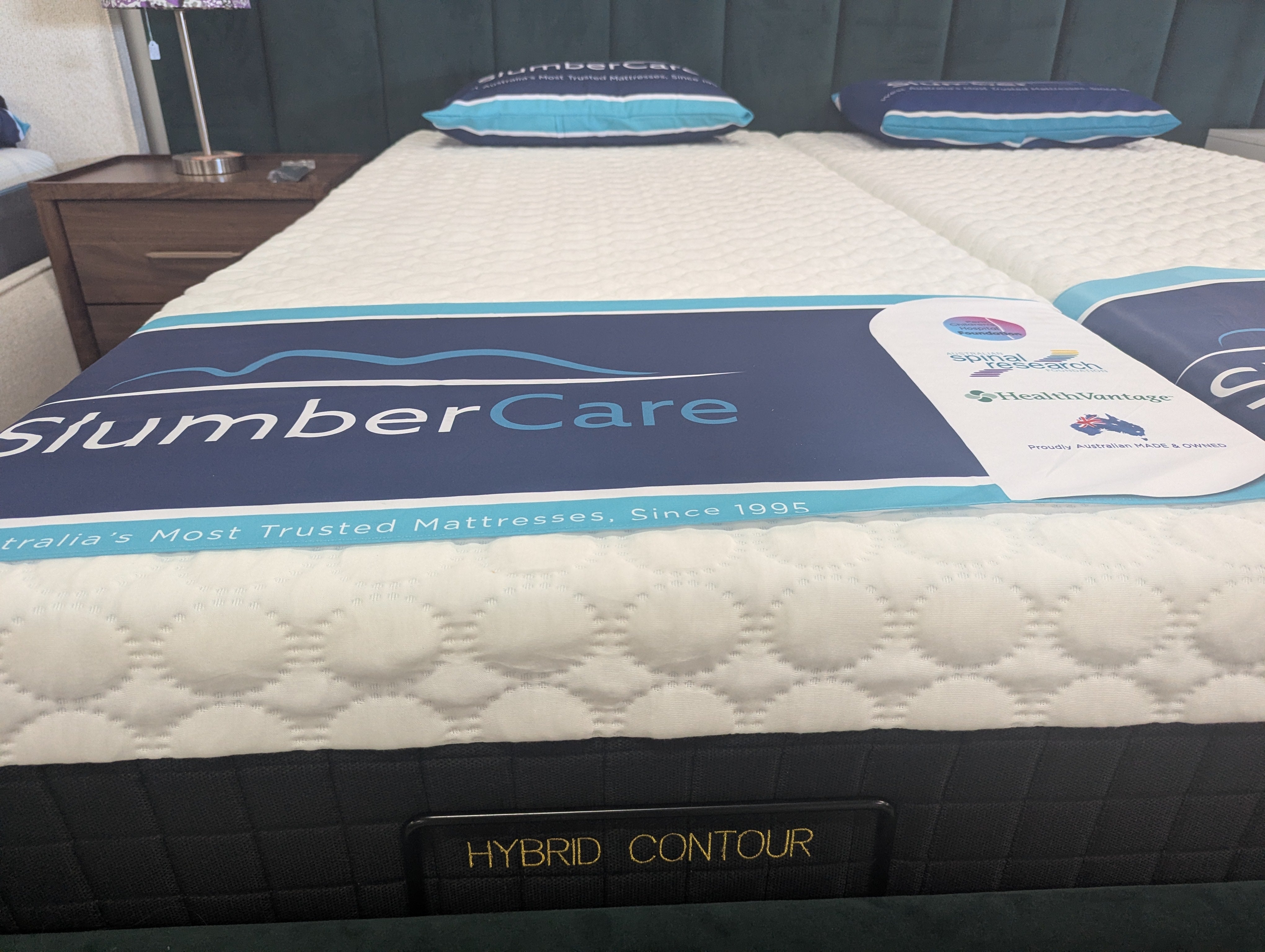 Close-up hybrid contour mattress top, white quilted surface with blue SlumberCare label.
